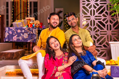 Preview: Cheerful Indian couples and friends celebrating Diwali at home with drinks, sweets, taking selfies
