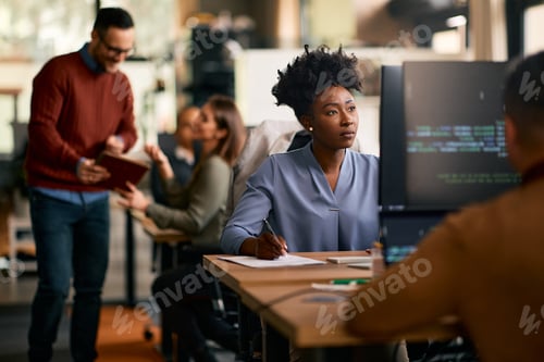 Preview: Black female graphic designer working on computer in the office.