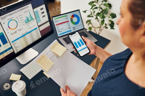 Preview: Businesswoman working with financial data on charts and tables on smartphone and computer