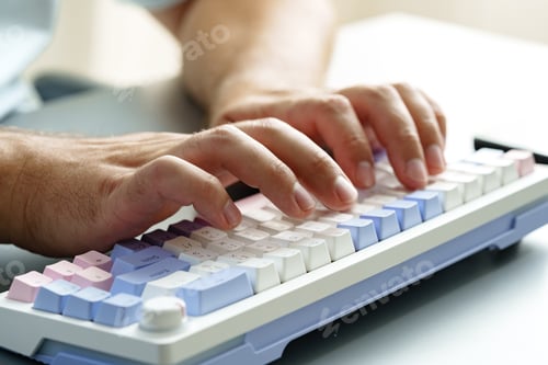 Preview: Hands typing on a colorful keyboard in an office setting during daytime work hours