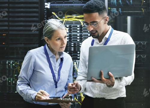 Preview: Connecting you is what they do. Shot of two technicians working together in a server room.