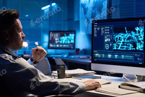 Preview: Man Analyzing Data on Computer Monitors at Night