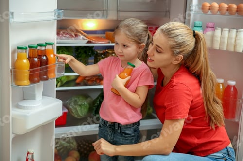 Preview: Young mother and daughter choosing juice in refrigerator at home