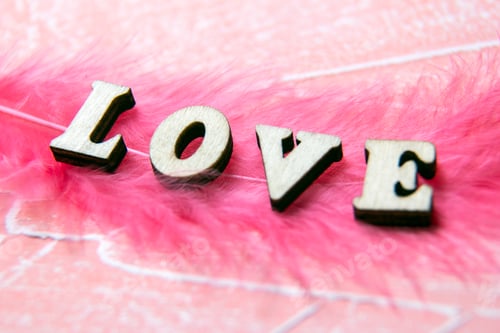 Preview: The inscription love on a pink background. inscription in wooden letters on a pink background.