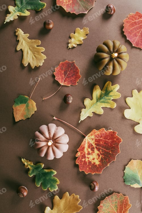 Preview: Burning candle shape of pumpkins, autumn leaves on brown background. Autumn, halloween concept