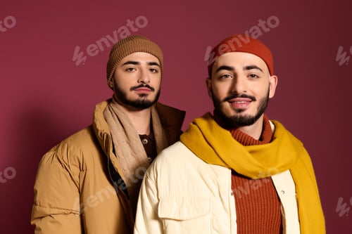 Preview: Stylish twins wearing winter fashion against a vibrant background in a modern setting