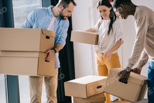 Preview: young multiethnic people carrying cardboard boxes during relocation