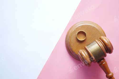 Preview: Divorce concept with gavel and wedding rings on table.