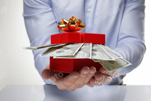 Preview: Man holding gift box with dollar banknotes on white background, closeup