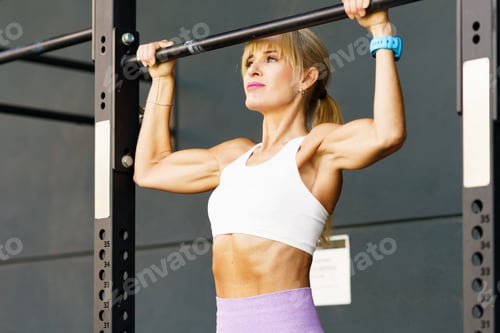 Preview: Strong sportswoman doing pull ups on bar