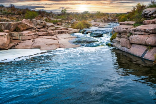Preview: A small shining stream flows among smooth wet and dark stones
