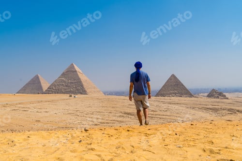 Preview: A young man in a blue turban walking next to the Pyramids of Giza