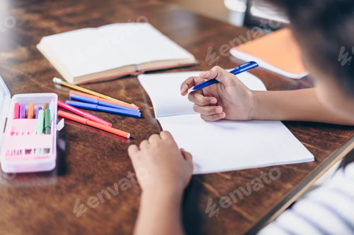 Preview: Closeup shot of a little girl writing in her notebook at the kitchen table.