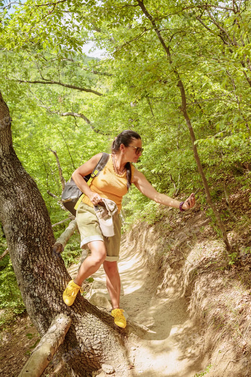Preview: Woman walking along forest path and using smartphone