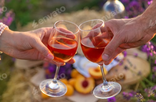 Preview: Wine in glasses is held by a woman and a man in a lavender field. Selective focus.