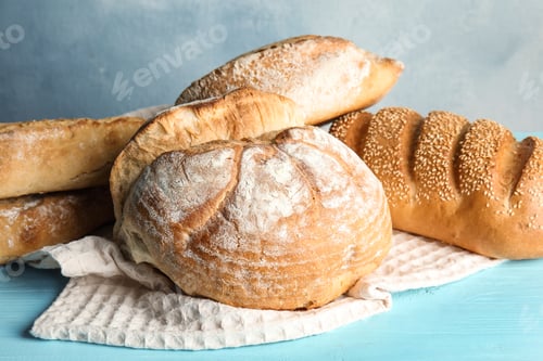 Preview: Pile of fresh bread on table against color background, closeup