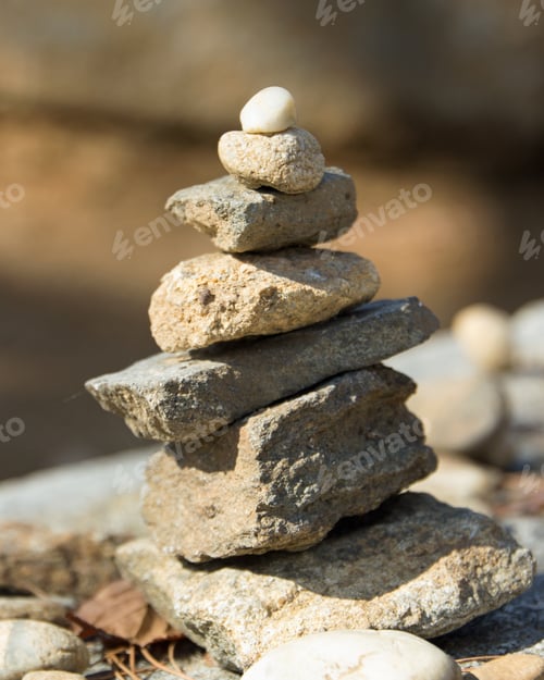 Preview: Vertical picture of stones on top of each other under the sunlight with a blurry background
