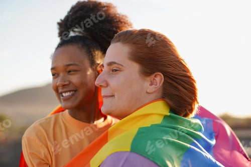Preview: Lesbian couple having tender moment together at gay pride parade with LGBT rainbow flag