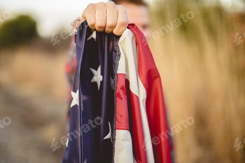 Preview: Closeup shot of a male holding the flag of the United States