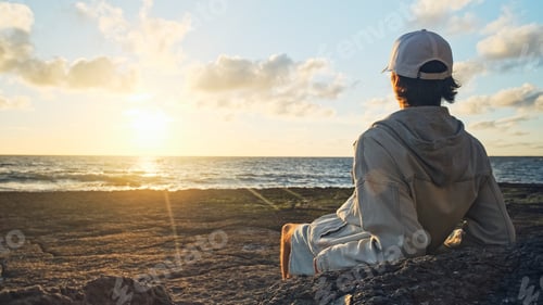 Preview: Man on a beach is looking distance during beautiful summer sunset.