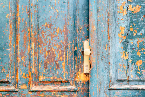 Preview: Old wooden door with peeling blue paint and beige handle