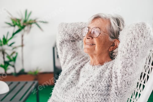 Preview: Portrait of senior attractive woman with smile relaxing at the armchair in the balcony at home