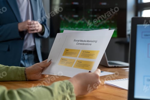 Preview: Hands of young businesswoman holding papers with marketing considerations