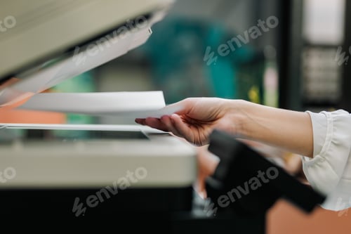 Preview: Female hand holding a paper, putting it on a scanner.