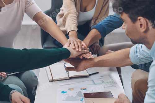 Preview: Close-up top view of modern business team keeping hands clasped while sitting in the office together
