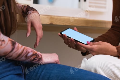 Preview: Unrecognizable women using smartphone together in bar