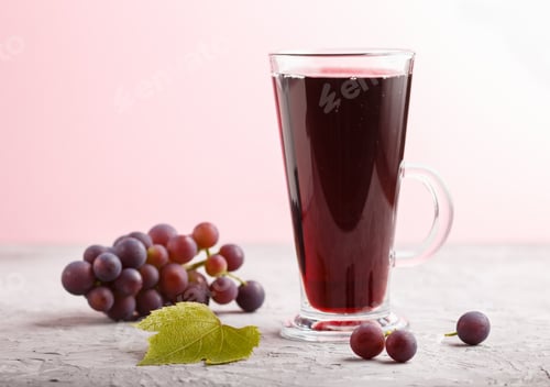 Preview: Glass of red grape juice on a gray and pink background. Side view