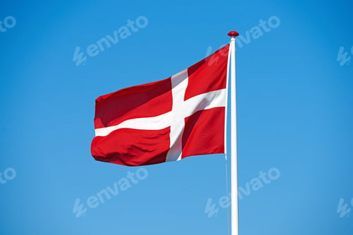 Preview: The Danish Flag. Shot of the Danish flag blowing against a blue background.