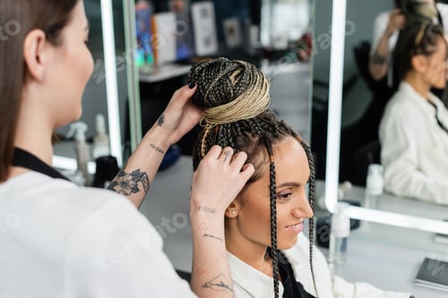 Preview: salon experience, tattooed hairdresser doing hair bun to female client with braids, cheerful women,