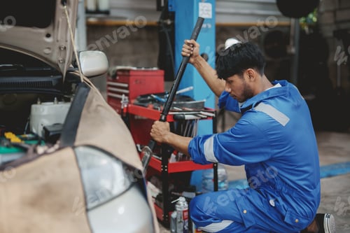 Preview: Asian auto mechanic changing tires. Asia Man picks up a car jack to change a tire.