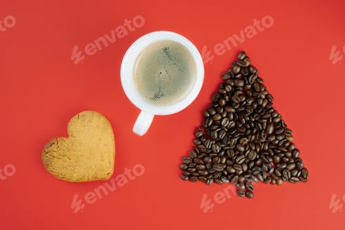 Preview: Brown coffee beans laid out in shape of Christmas tree with cup of coffee and heart-shaped cookie on