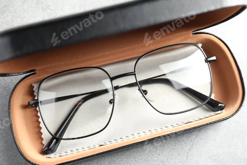 Preview: Case with stylish glasses and cleaning cloth on grey table, top view