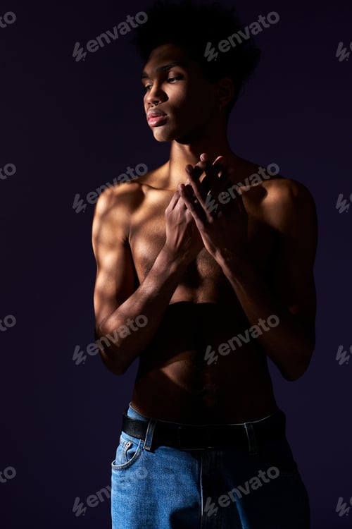 Preview: Portrait of transgender hispanic model with naked torso. Trans gender young man standing in shadow