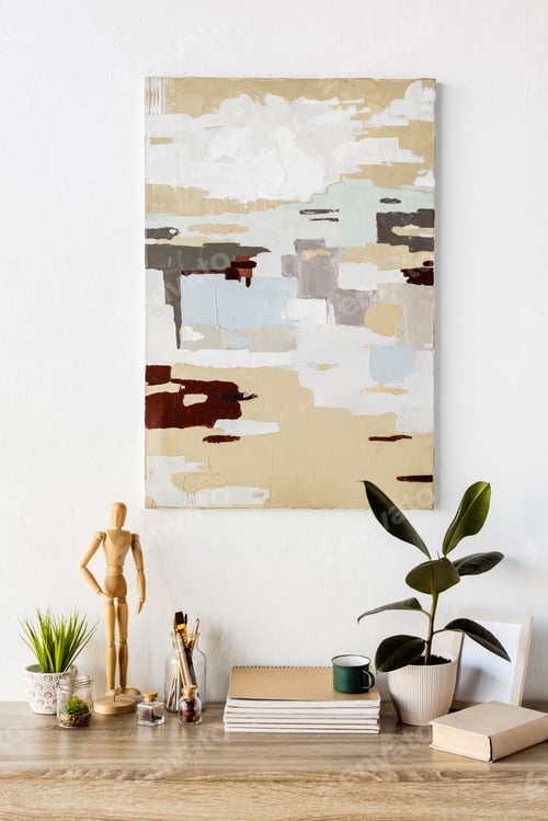 Preview: painting on wall near table with wooden mannequin, plant, notebooks, book, cup, vase with wheat and