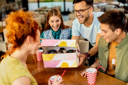 Preview: Happy man surprising his friends with box of donuts.