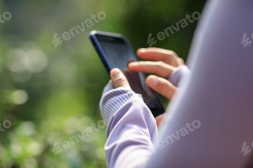 Preview: Asian woman using smartphone outdoors