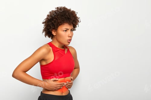 Preview: Shot of dissatisfied Afro American woman suffers from painful feelings in stomach, touches belly, br