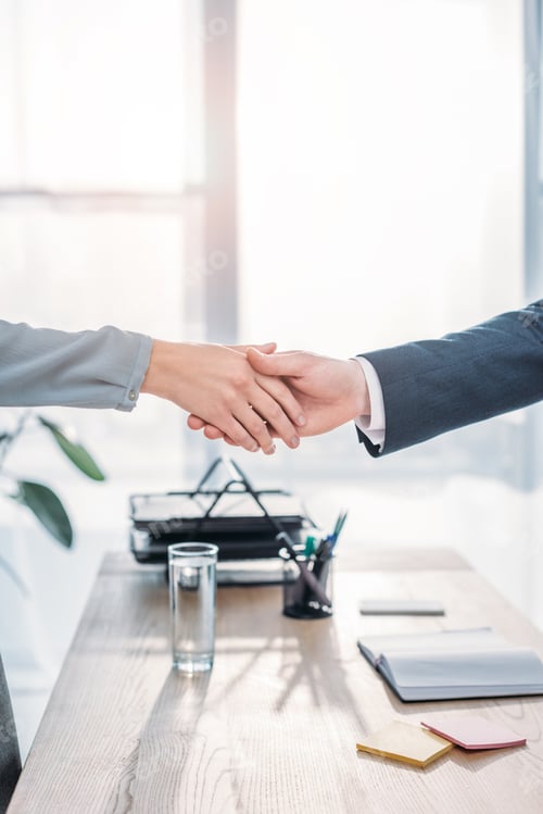 Preview: cropped view of recruiter and employee shaking hands in modern office