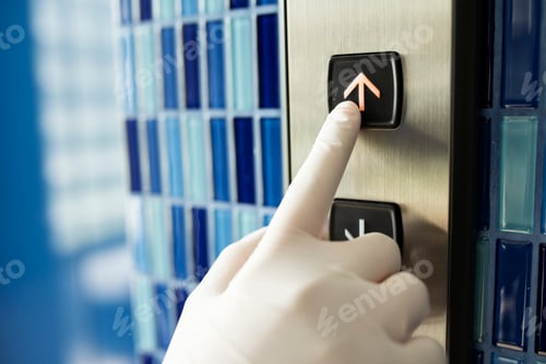 Preview: Gloved hand pressing an elevator button to prevent coronavirus contamination
