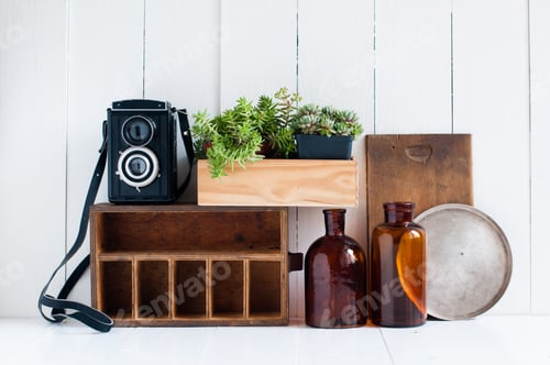 Preview: Vintage Home Decor: Old Wooden Boxes, Houseplants, Camera And Old Brown Glass Bottles On White