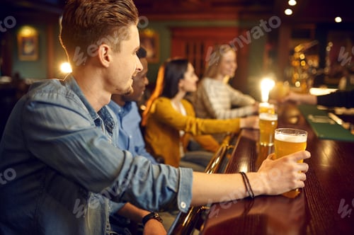 Preview: Cheerful friends drinks beer at the counter in bar