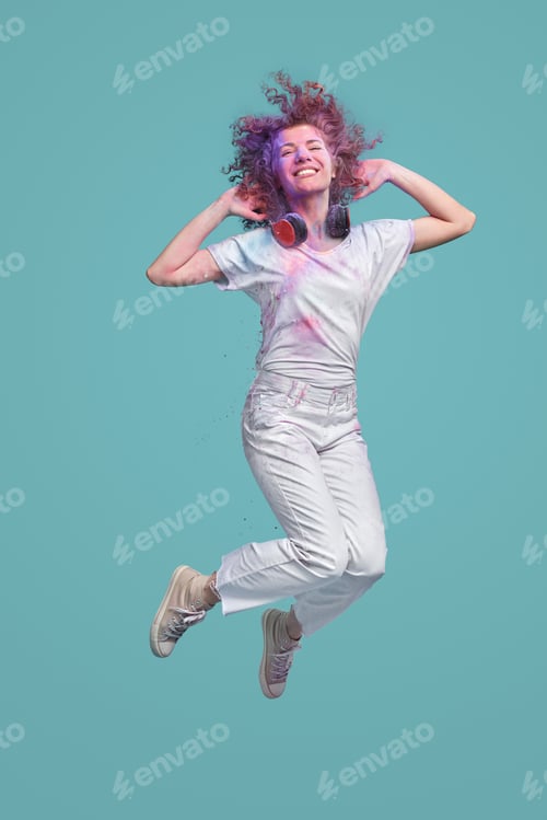 Preview: Cheerful woman jumping during Holi festival