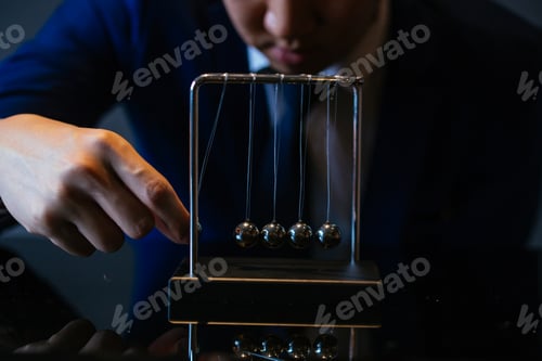Preview: Cropped shot of businessman pulling ball of Newton cradle