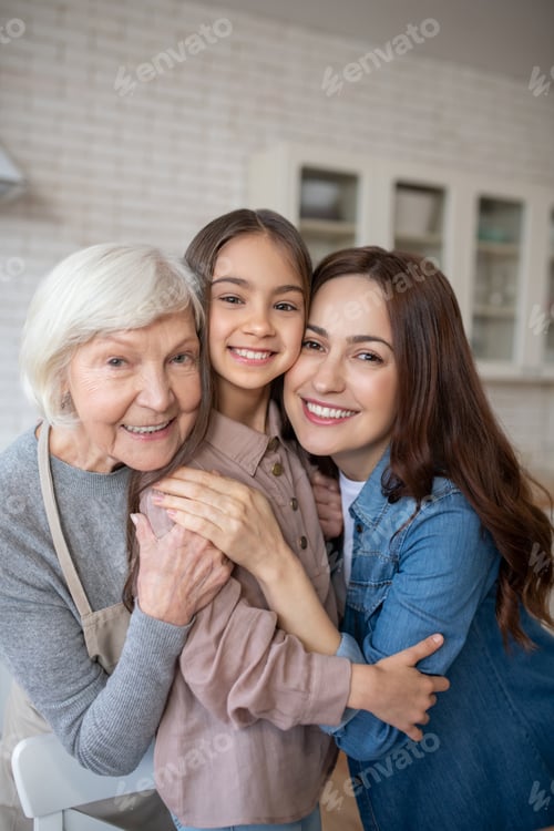 Preview: Three happy women hugging together in the kitchen.