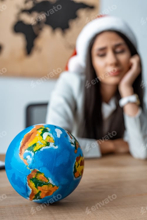 Preview: selective focus of pensive travel agent near globe at workplace