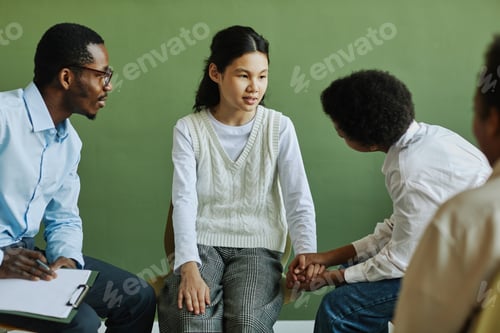 Preview: Youthful schoolgirl talking to schoolboy holding her hands during communication